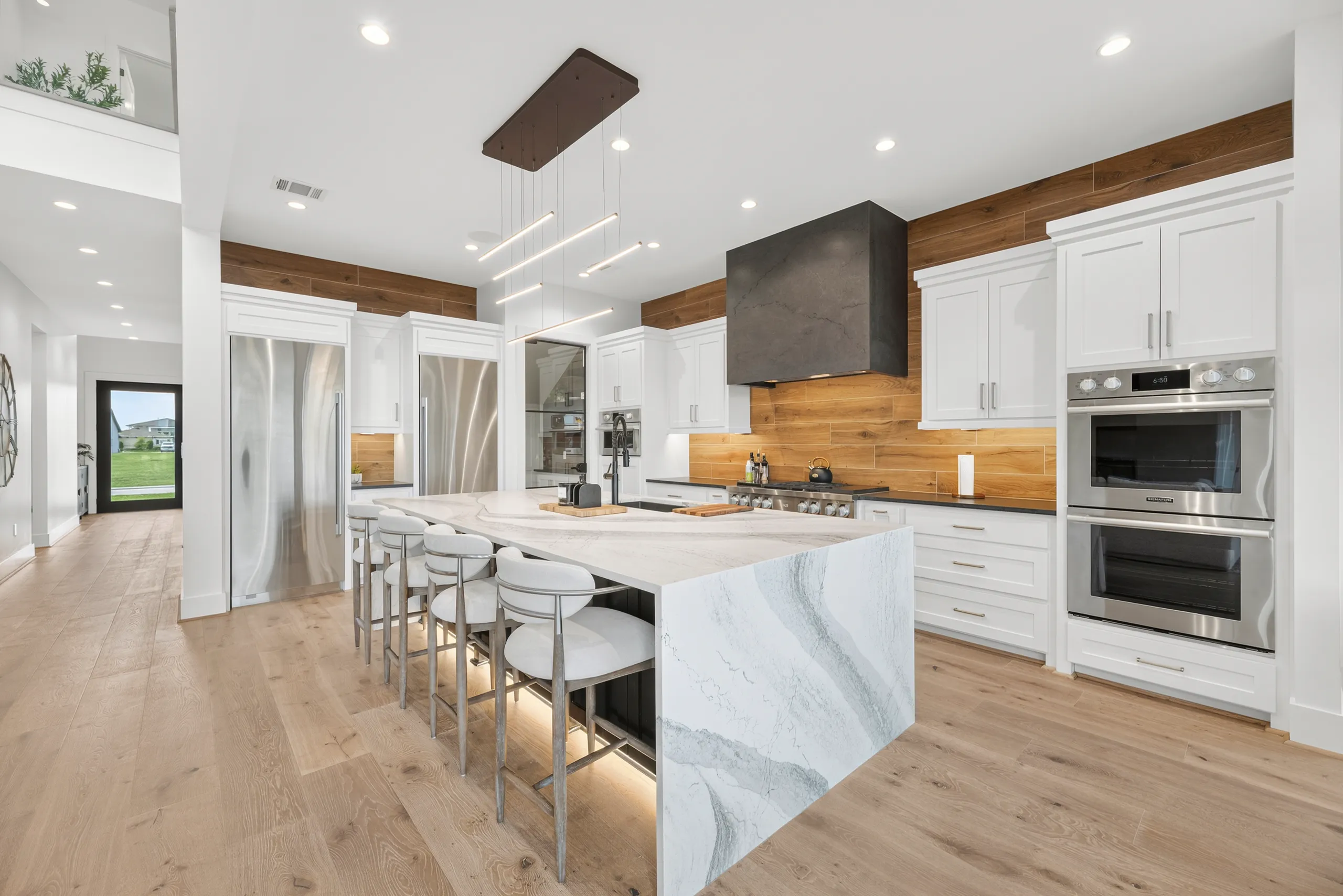 Chef’s kitchen with waterfall marble island and white-oak tile